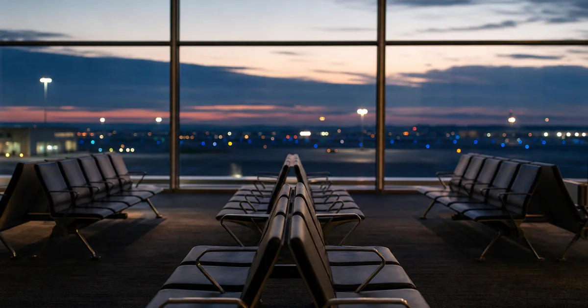 An airport departure lounge at dawn, rows of empty seats facing wide windows with runway lights fading outside