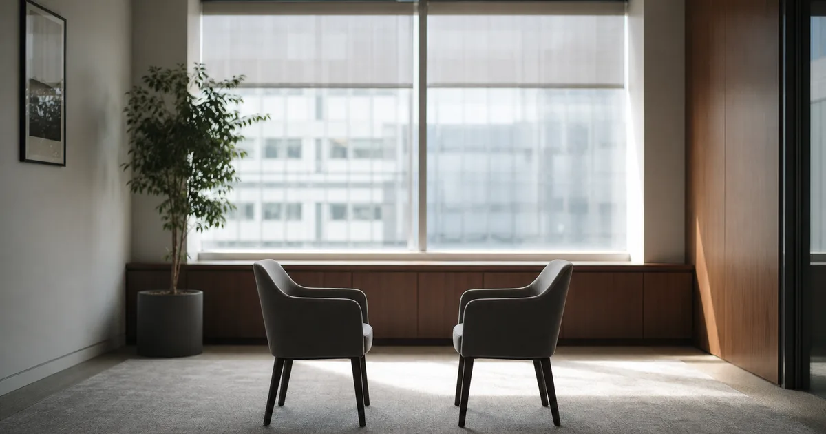 A corporate HR interview room at midday, two chairs facing a window with soft diffused light