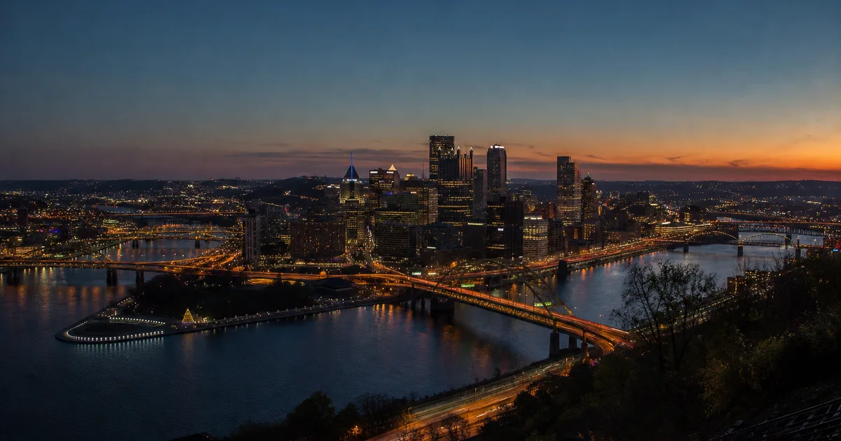 Evening view of Pittsburgh from the top of Mount Washington, the confluence of three rivers glowing below as bridges and downtown towers light up against a