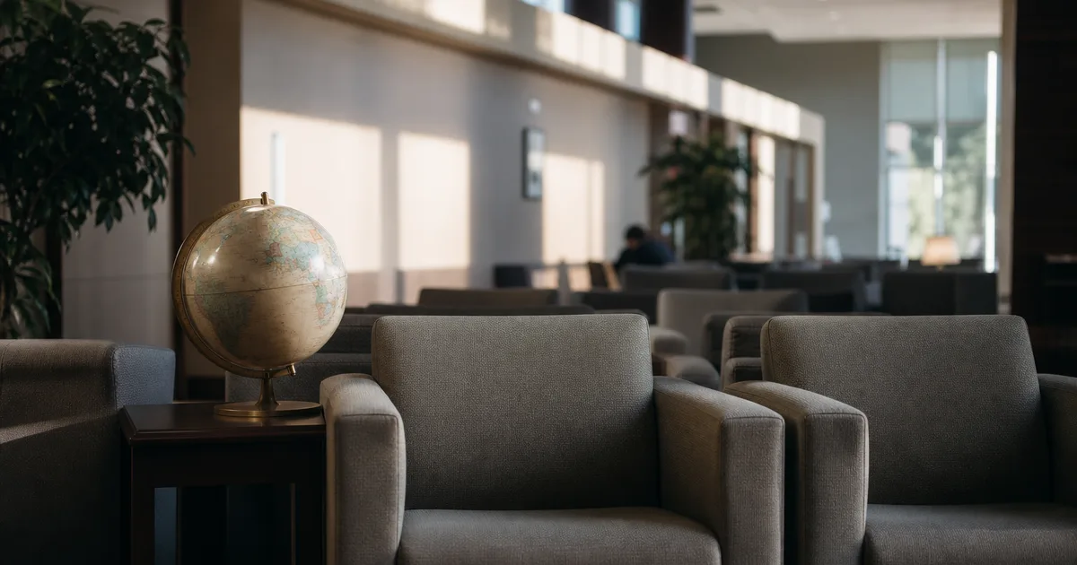 An international student services waiting area on a US campus at early morning, rows of empty upholstered chairs and a globe on a side table, soft daylight