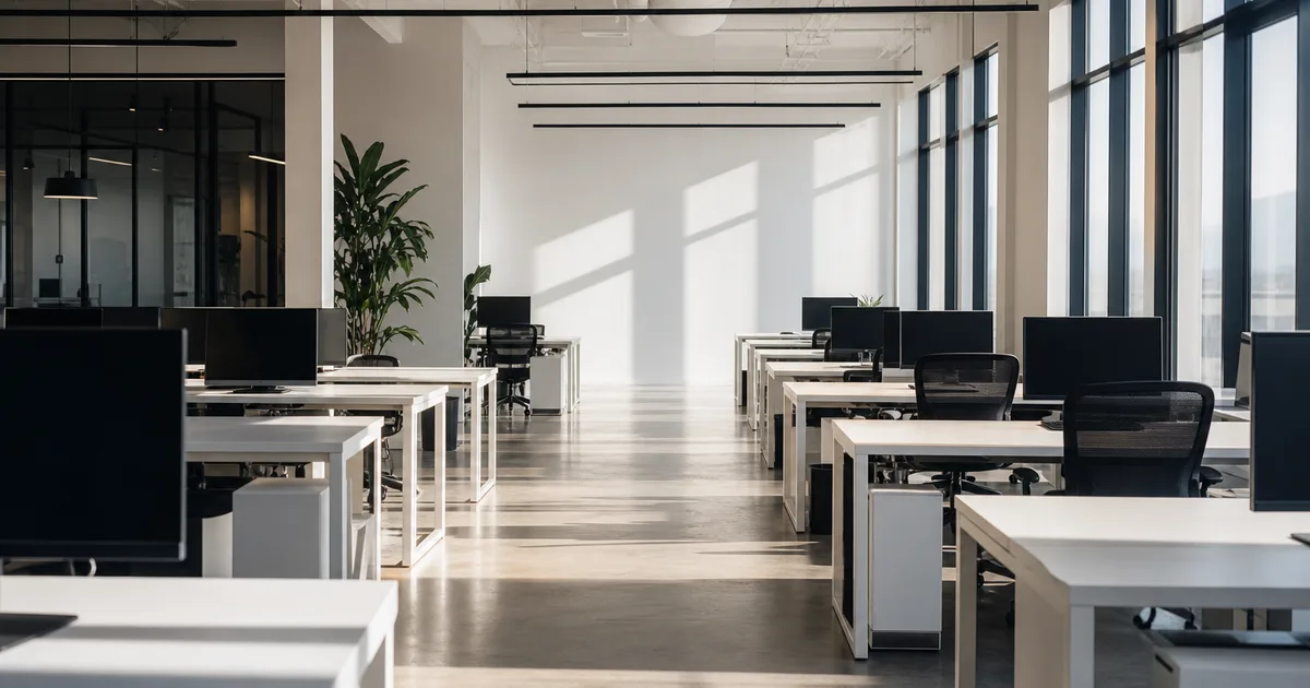 A modern open-plan fintech office with exposed brick, empty standing desks and soft overhead lighting at dusk